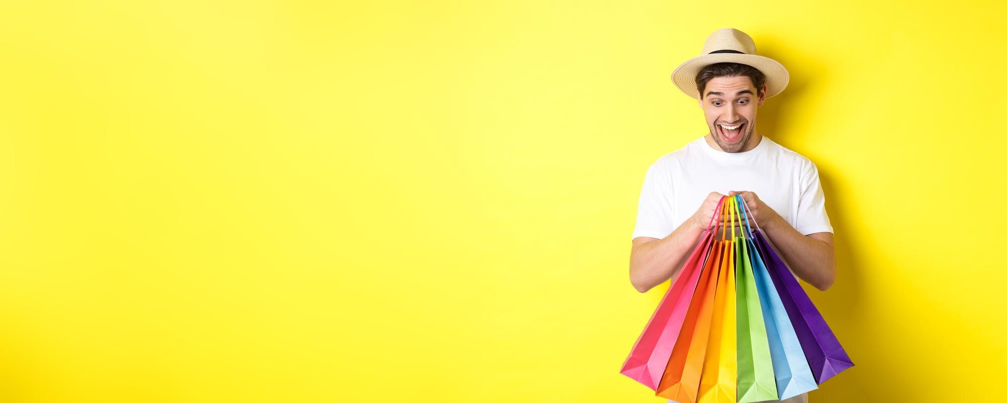 happy-man-shopping-vacation-holding-paper-bags-smiling-standing-against-yellow